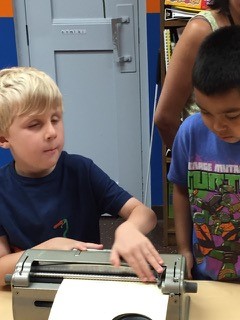 BELL student teaching Braille to a guest
